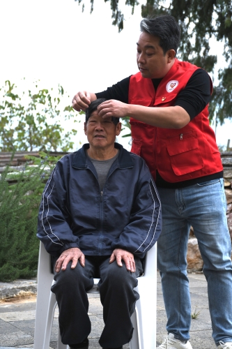 图为2025年12月5日“时光里”志愿服务者为老人整理仪容